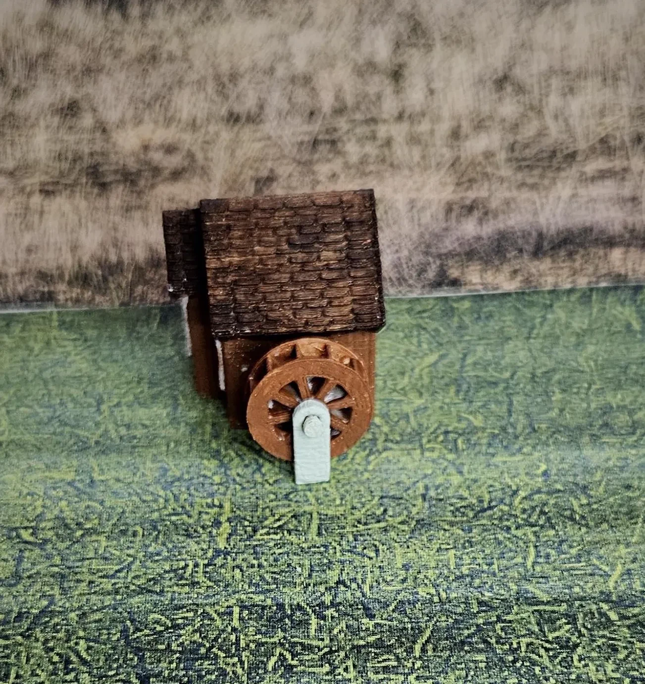 Side view of N scale waterwheel with small building